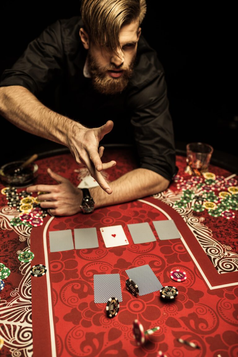 Emotional bearded man throwing poker chips on table while playing poker